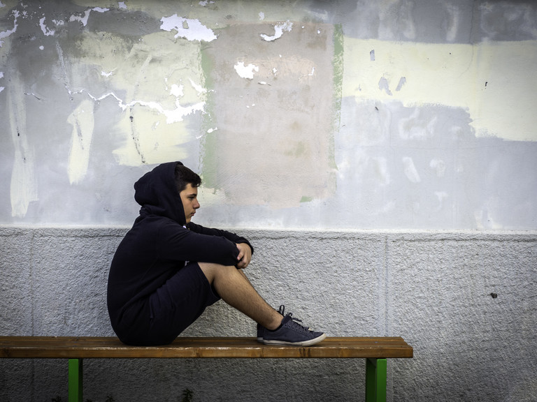 Junge mit Hoodie sitzt auf Bank - Immanuel Beratung Junge mit Hoodie sitzt auf Bank - Immanuel Beratung